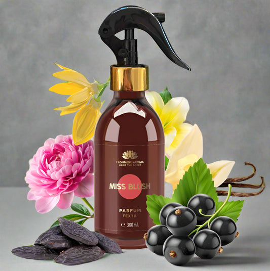 Miss Blush perfume bottle with flowers, black currants, and vanilla beans on a white background